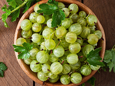 Green gooseberries in a wooden bowl